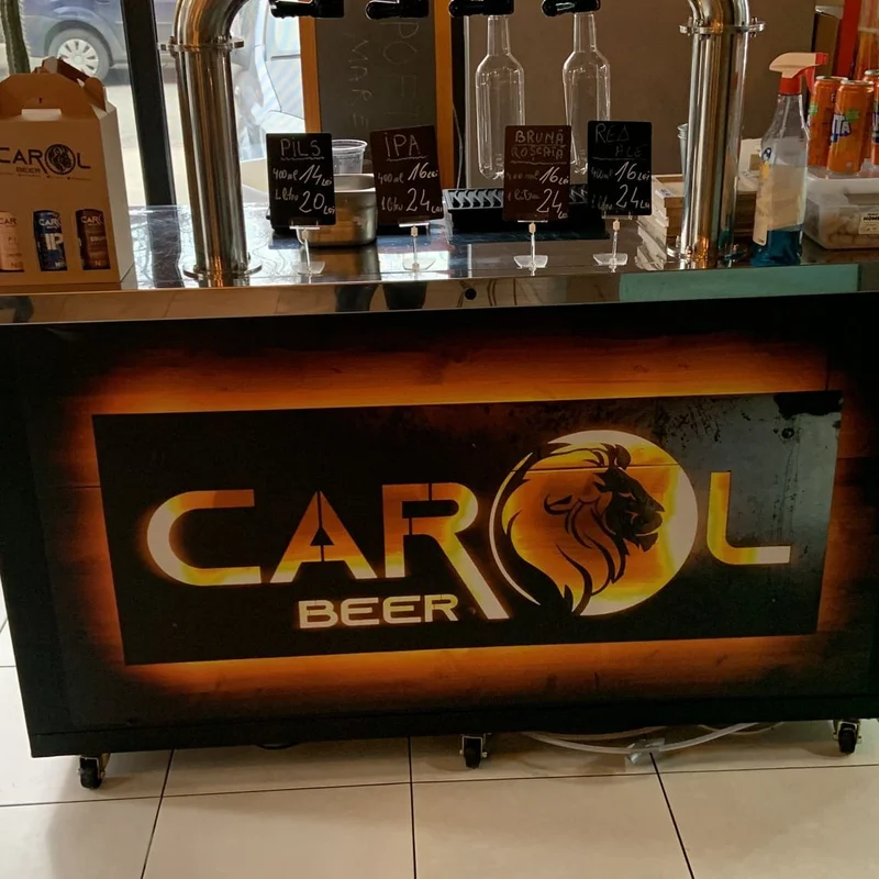 Colantare front bar bere artizanala cu logo iluminat retroiluminat — "Bere Artizanala" cu silueta de leu in finisaj gold, instalat in interior pub cu robinete de bere artizanala si tablite ardezie cu preturi PILS, IPA, BRUNA, ROSCATA