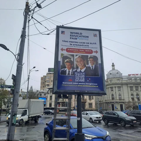 Citylight Mora Group cu campanie targ educational pentru licee de elita in strainatate, montat in Piata Romana cu cladirea Academia de Studii Economice (cupola si fatada www.ase.ro) in fundal si indicator Bulevardul Dacia
