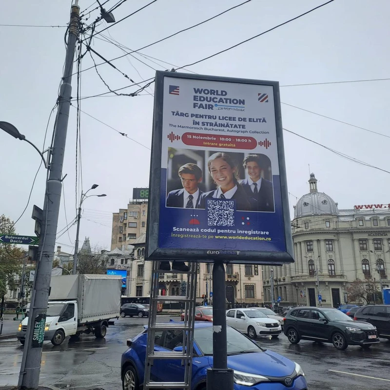 Citylight Mora Group cu campanie targ educational pentru licee de elita in strainatate, montat in Piata Romana cu cladirea Academia de Studii Economice (cupola si fatada www.ase.ro) in fundal si indicator Bulevardul Dacia