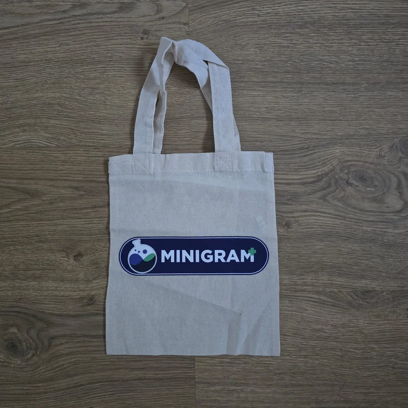 Sacosa de cumparaturi din bumbac reciclat natural 190 g/m² cu mânere lungi, personalizata cu logo client pe fata, dimensiuni 38 × 42 cm — produs promotional textil Mora Group fotografiat real pe fundal de lemn