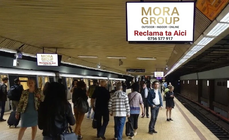 Ecran LED suspendat pe coloana intr-o statie Metrorex Bucuresti cu trafic mare de calatori